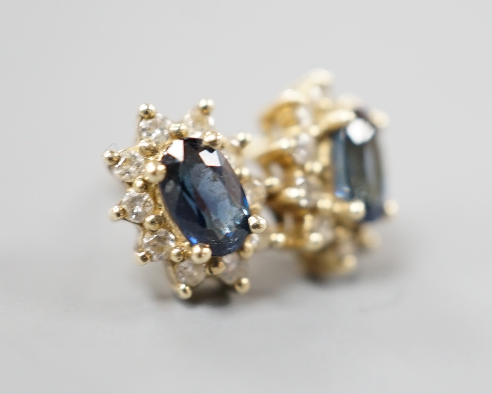 A pair of modern 9ct gold, sapphire and diamond chip set oval cluster earrings, gross 1.3 grams.